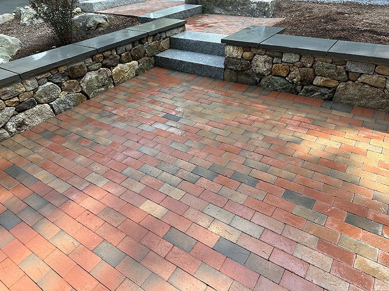 Custom patio with stone walls in Goffstown designed and installed by landscaping expert Nest Outdoors