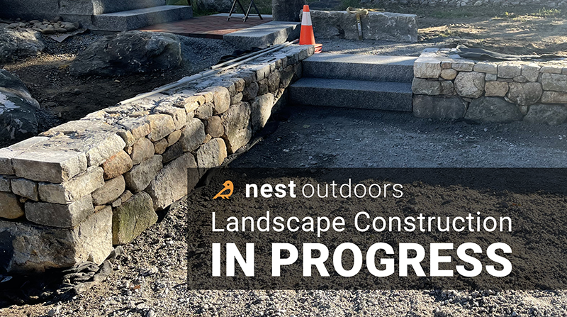 Custom stone wall build with landscape lighting in Goffstown NH by Nest Outdoors